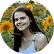 Naura Silvana Premium Care Premium Care Smiling woman with long dark hair wearing a white top posing outdoors among sunflowers in a field